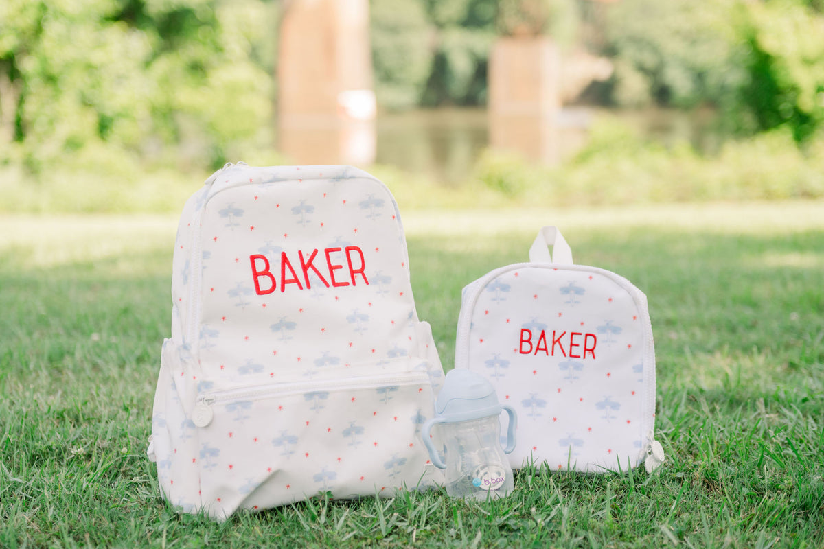 TRVL Backpacker with the TRVL Bring it Lunch Bag in the David's Airplane print with 'Baker' Embroidered on it. Also pictured is the dapper sippy straw cup in bubblegum.