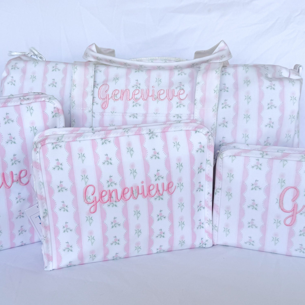 TRVL Weekender Duffle Bag with 'Genevieve' embroidered in a light pink scripty font, with the TRVL large roadie, medium roadie and small roadie also with embroiderey all in the Ribbon Floral Pink print.